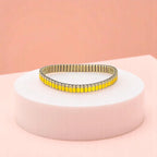 Bracelet on geometric prop with peach color gradient in the background.