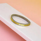 Bracelet on geometric prop with peach color gradient in the background.