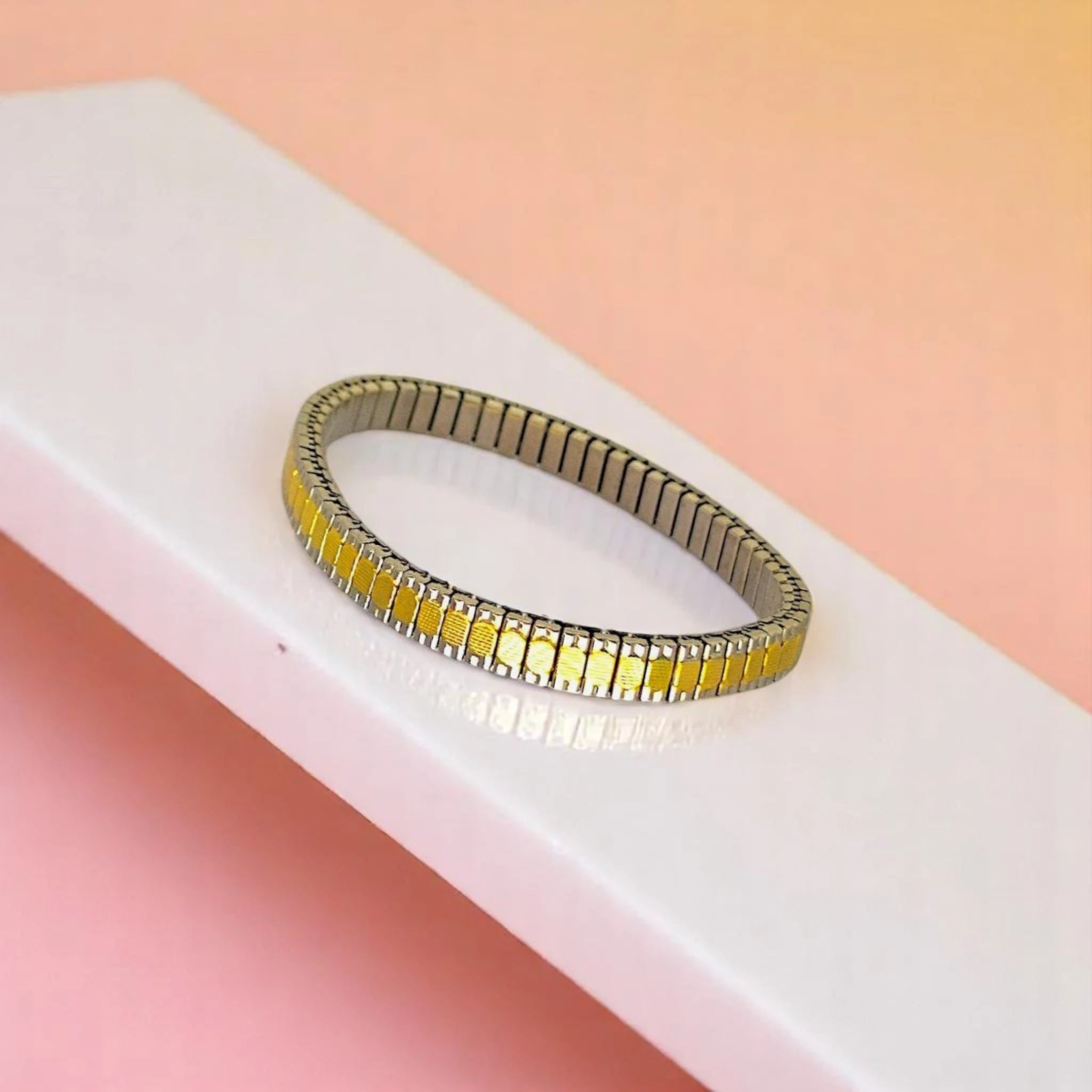 Bracelet on geometric prop with peach color gradient in the background.