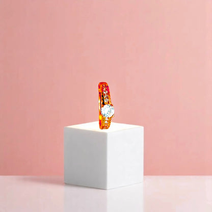Ring on a white cube geometric prop with a peach color gradient in the background.
