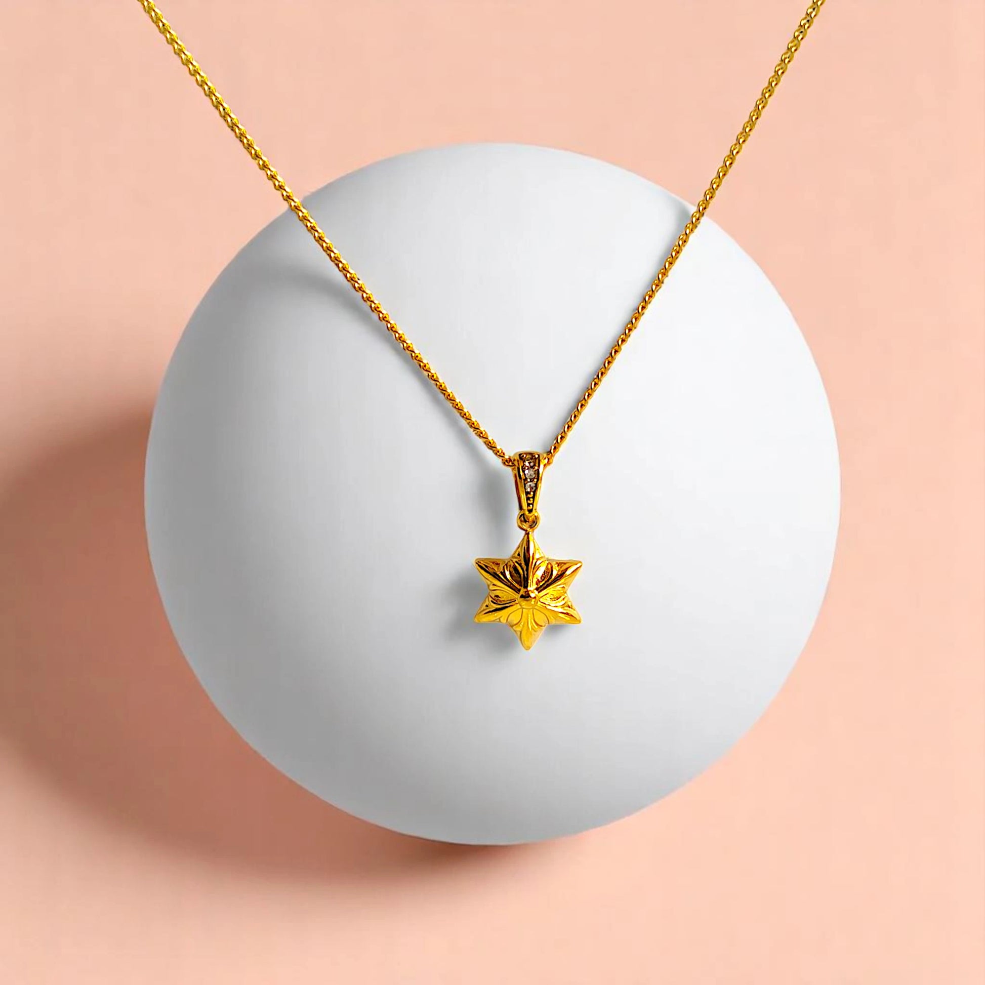 Necklace on a white geometric prop with a peach-colored gradient background.