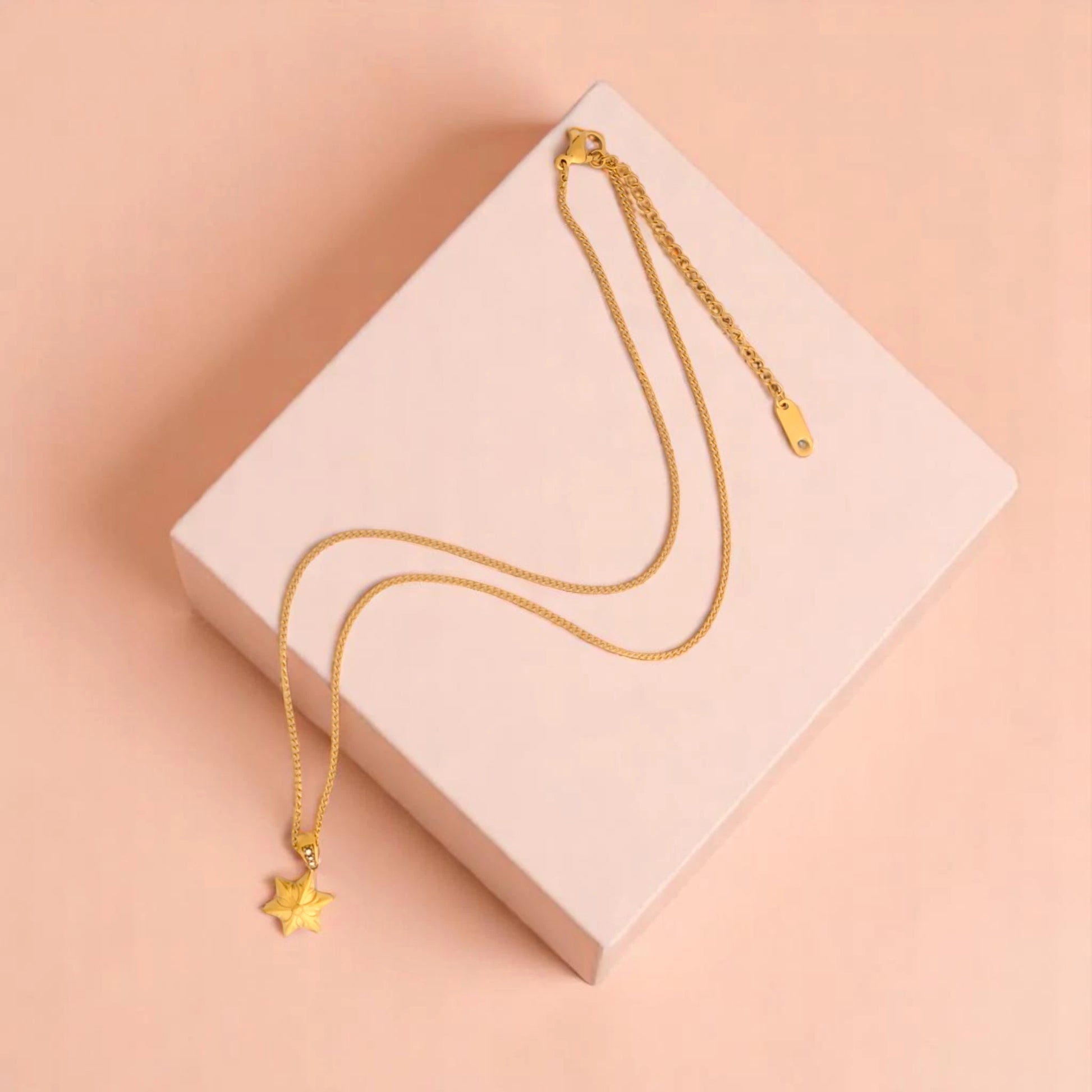 Necklace on a peach geometric prop with a peach-colored gradient background.