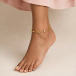 Indian woman foot pointed wearing gold infinity anklet with CZ stones, blush top.