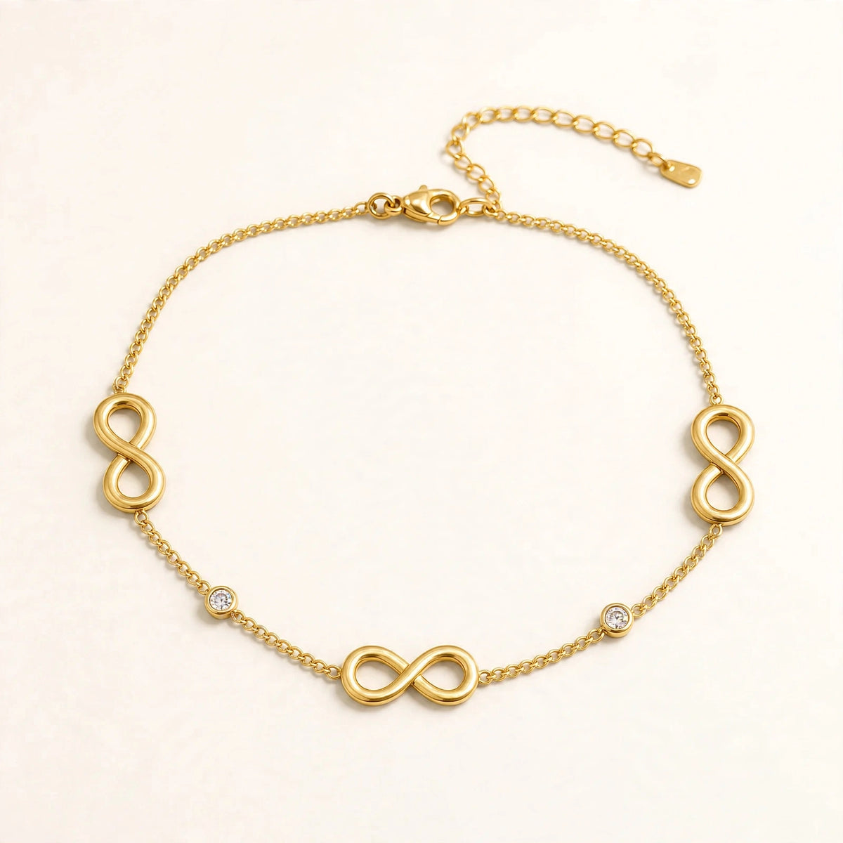 Gold infinity anklet with 3 infinity symbols and 2 bezel CZ stones, cable chain, lobster clasp.