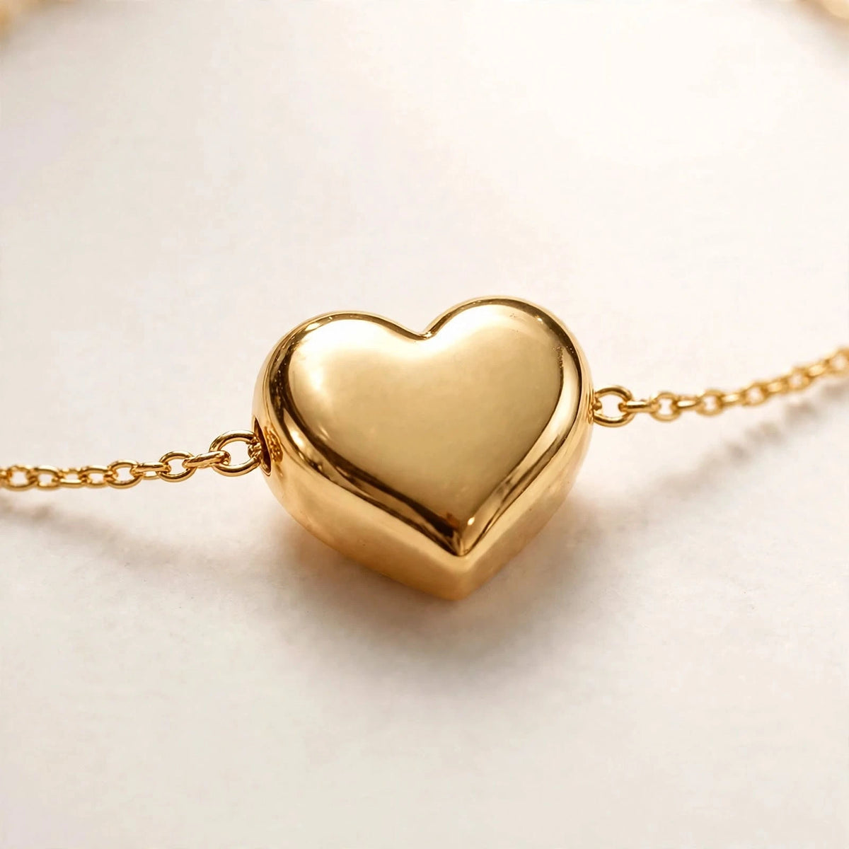 Extreme macro of gold puffy heart on delicate chain on white background