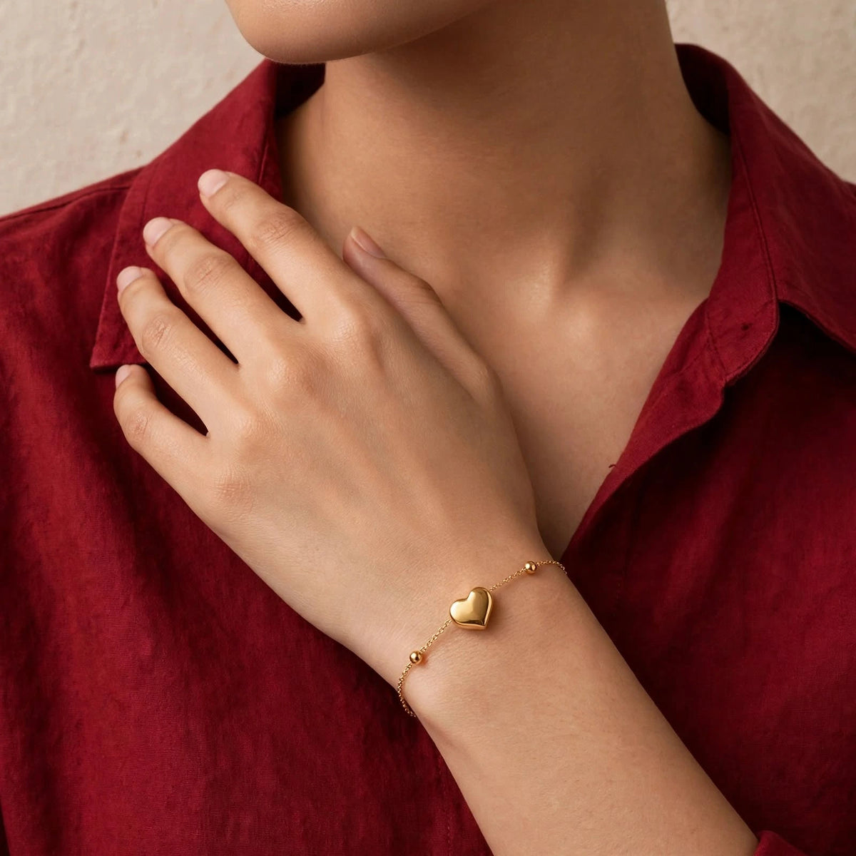 Indian woman in red shirt wearing minimal gold heart bracelet with 2 beads near collarbone
