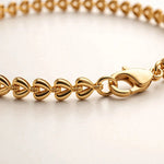 Extreme macro of gold teardrop chain links and lobster clasp, polished detail.