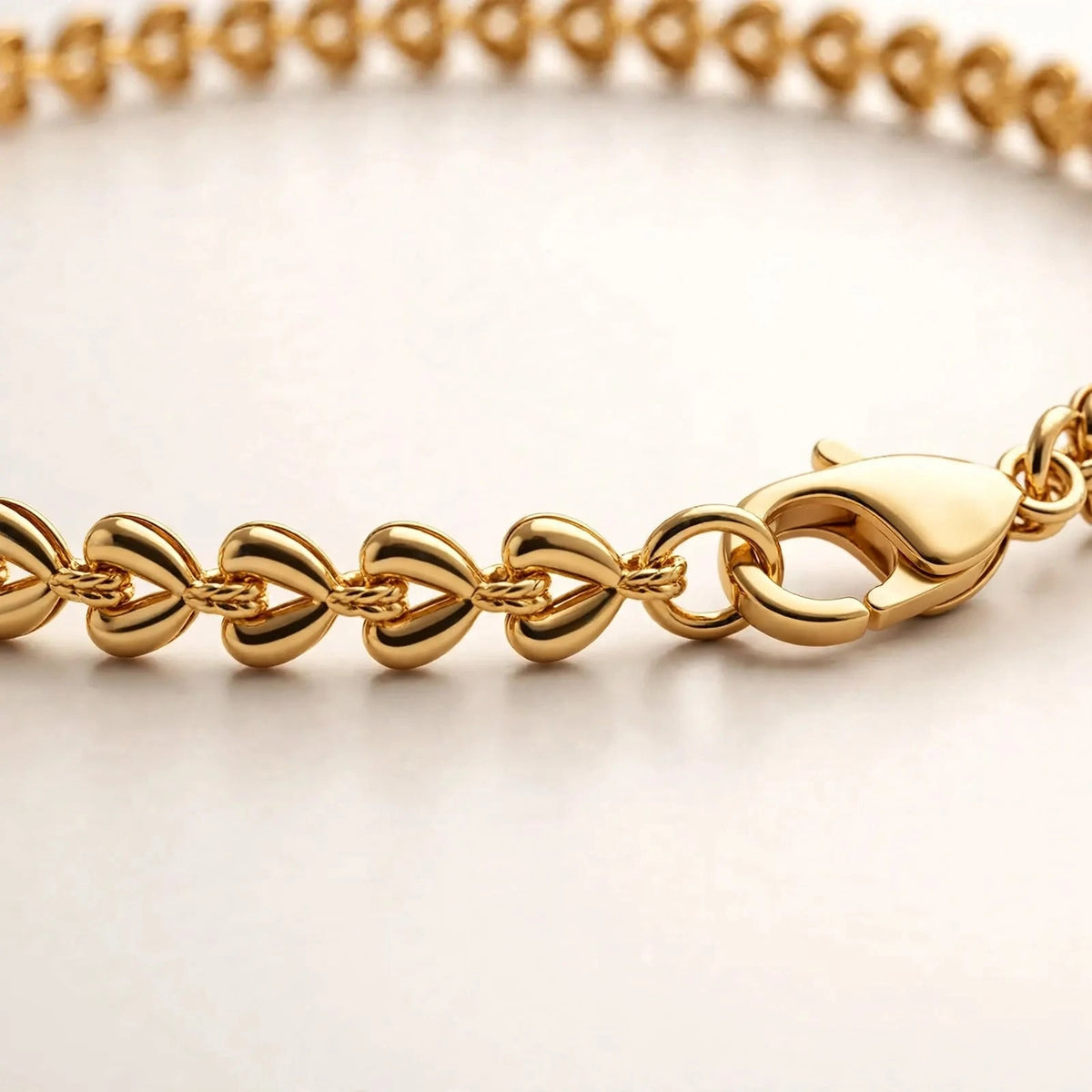 Extreme macro of gold teardrop chain links and lobster clasp, polished detail.
