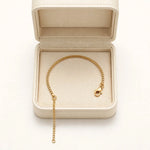 Gold box chain bracelet on open cream leather jewellery box on warm white