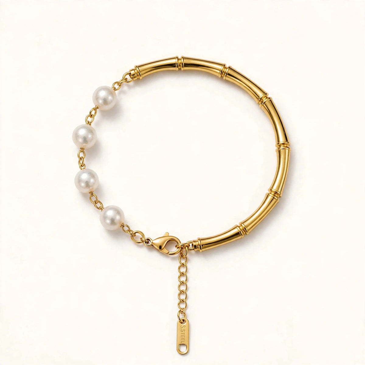 Side angle view of gold bamboo pearl bracelet with pearl-side extension and gold S.STEEL tag reaching lobster clasp