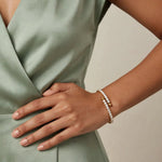 Gold spiral bypass bracelet single wrap on wrist, sage blouse, nude manicure.