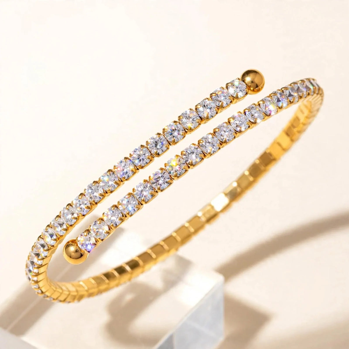 Side angle of gold spiral tennis bracelet showing depth and ball ends on riser.