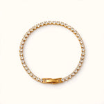 Gold tennis bracelet with round cubic zirconia stones in circle, clasp bottom on bright warm white