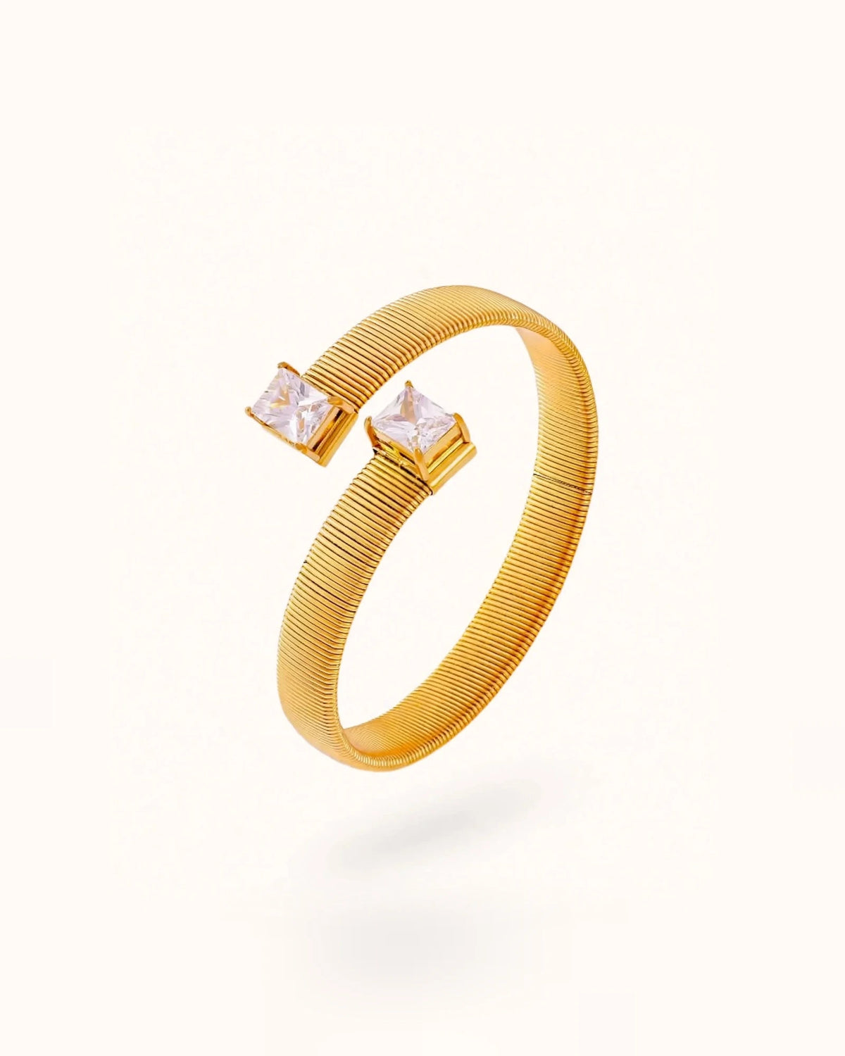 Gold dual CZ open cuff bracelet with rectangular stones on off-white background