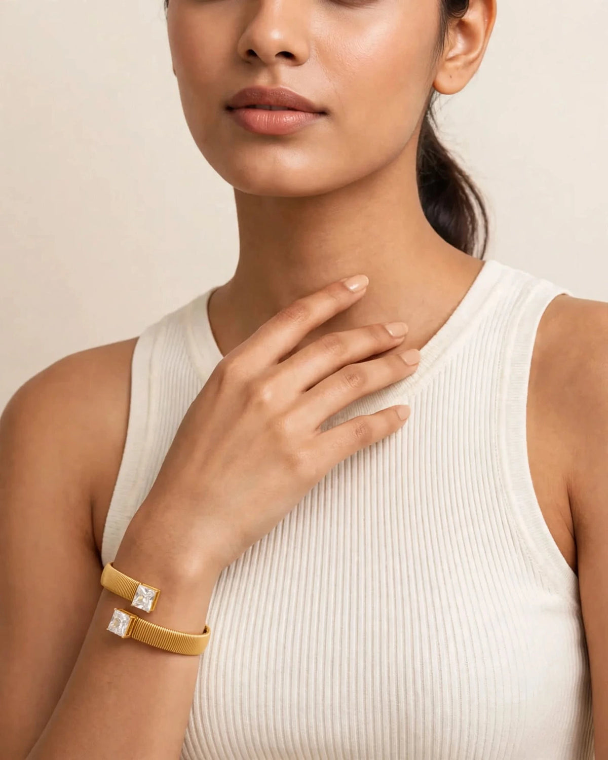 Indian woman in ivory top wearing gold dual CZ cuff bracelet, hand on collarbone
