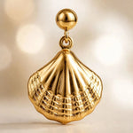 Extreme macro of gold shell drop earring showing polished dome and textured shell detail.