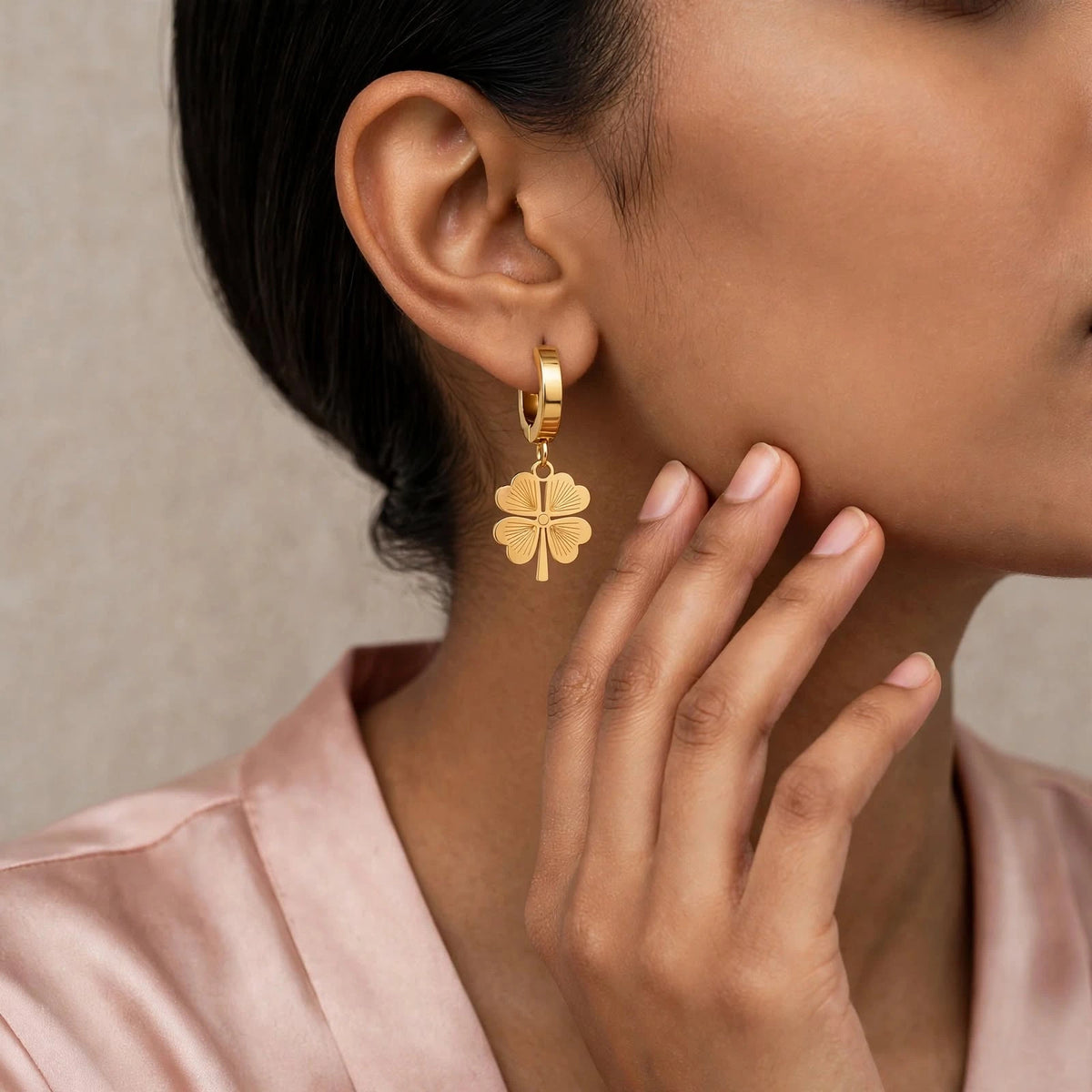 Indian woman wearing gold clover drop earrings close-up ear and jaw