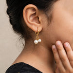 Gold hinged hoop with twin pearls on ear, fingertips at jaw, black silk pavadai