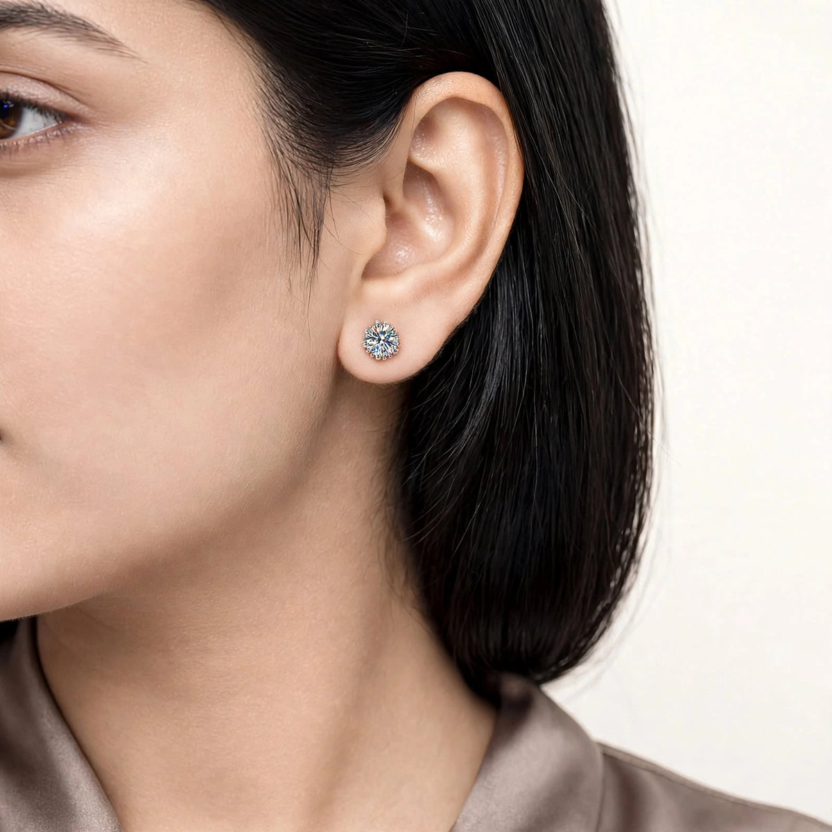 Modern fair skin model wearing small 6-prong diamond studs taupe blouse.