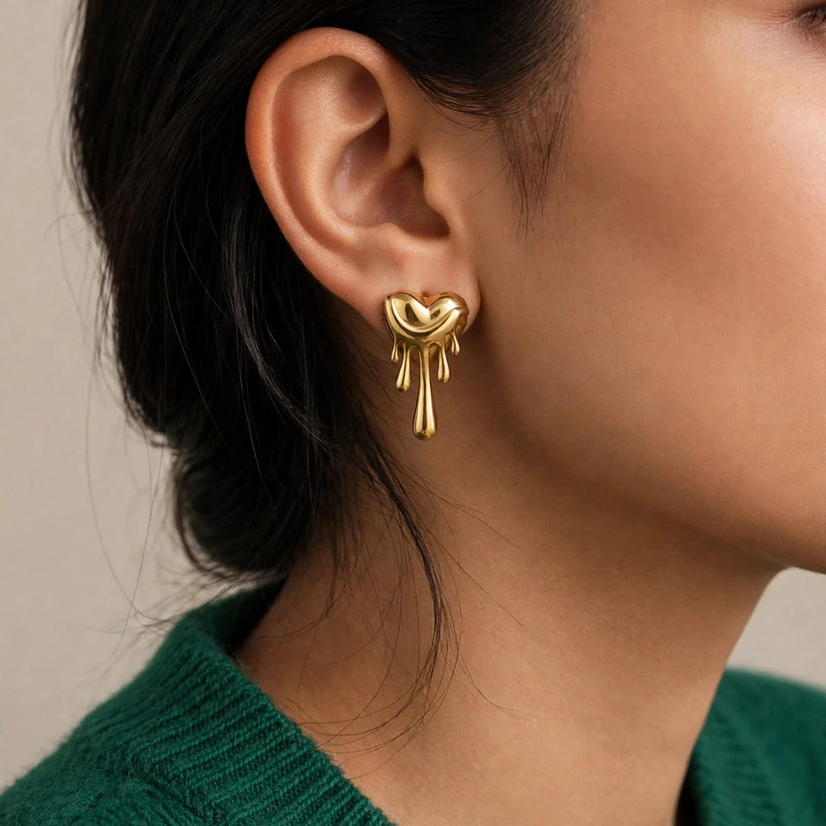 Indian woman in emerald sweater with hair tucked, wearing gold melting heart earrings in profile.