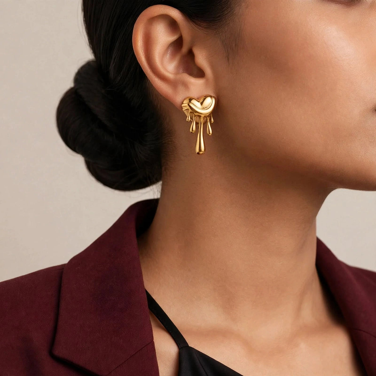 Indian woman with sleek low bun in wine blazer wearing gold melting heart drip earrings.