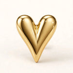 Glossy gold puffed heart stud earring macro on off-white background