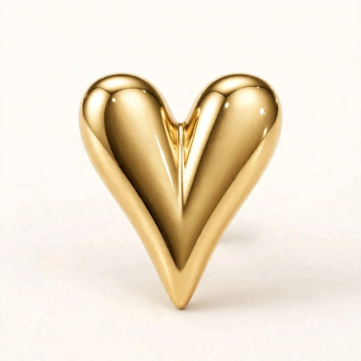 Gold puffy heart stud earrings on beige stone showing butterfly back detail.
