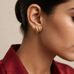 Indian woman in deep red silk wearing small gold puffed heart stud close-up