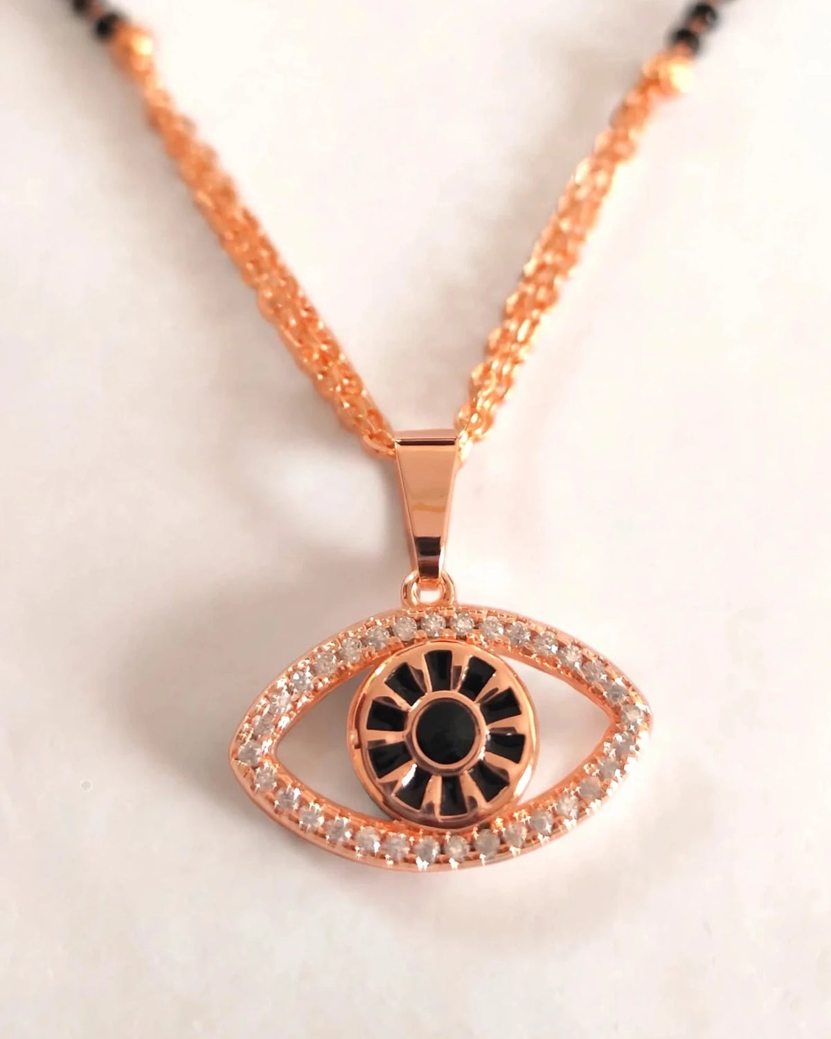 Extreme macro close-up of rose gold evil eye pendant with diamond border and black enamel detail