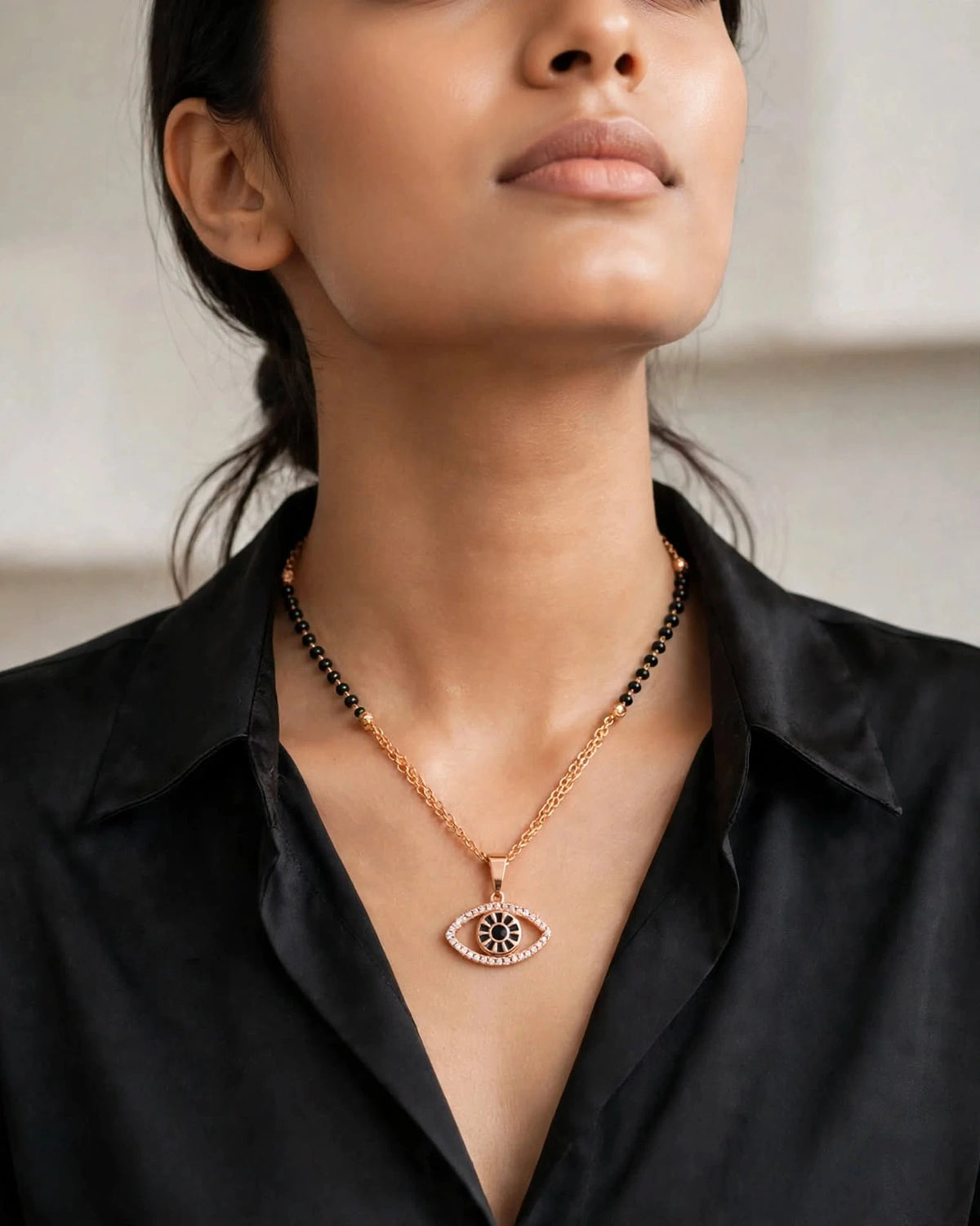 Indian woman in black silk shirt wearing rose gold evil eye mangalsutra with diamond eye pendant