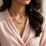 Indian woman in blush wrap blouse with smaller gold infinity necklace, face out of frame