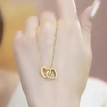 Hand holding gold double interlocked heart pendant necklace on delicate cable chain.