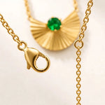 Close-up of gold lobster clasp and extension chain with emerald fan pendant