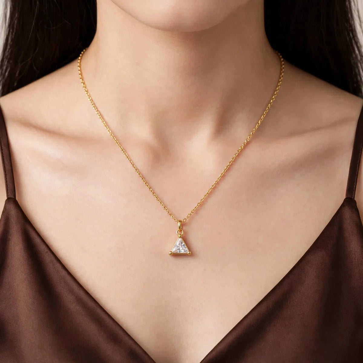 Model in brown satin V-neck wearing triangular crystal pendant on Singapore chain