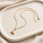 Triangular crystal pendant necklace on ceramic tray with linen