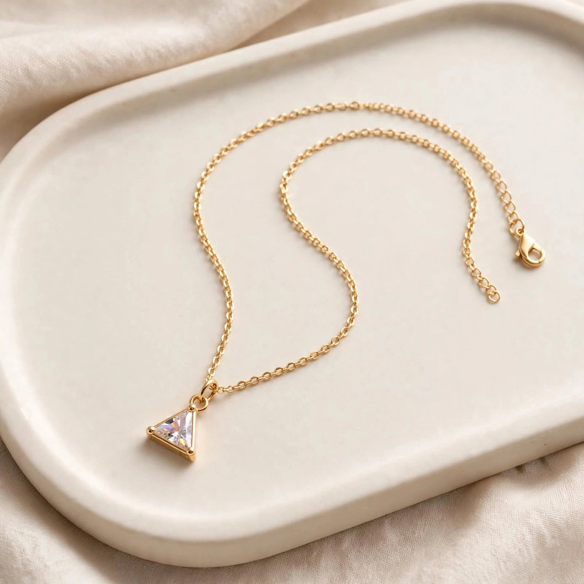 Triangular crystal pendant necklace on ceramic tray with linen