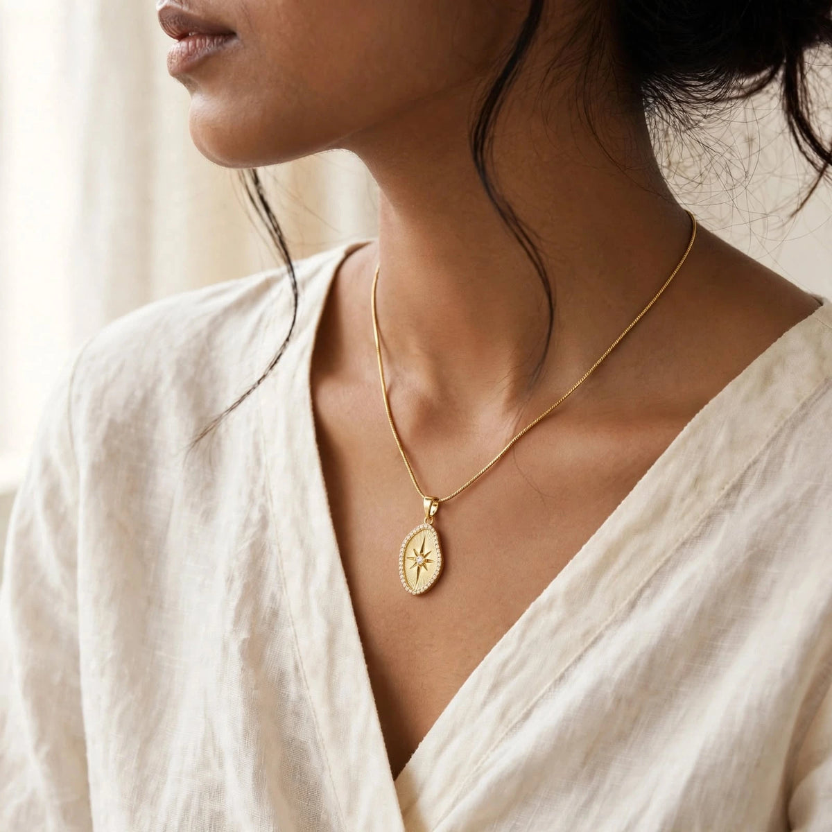 Indian woman in ivory wrap wearing small sunburst pendant