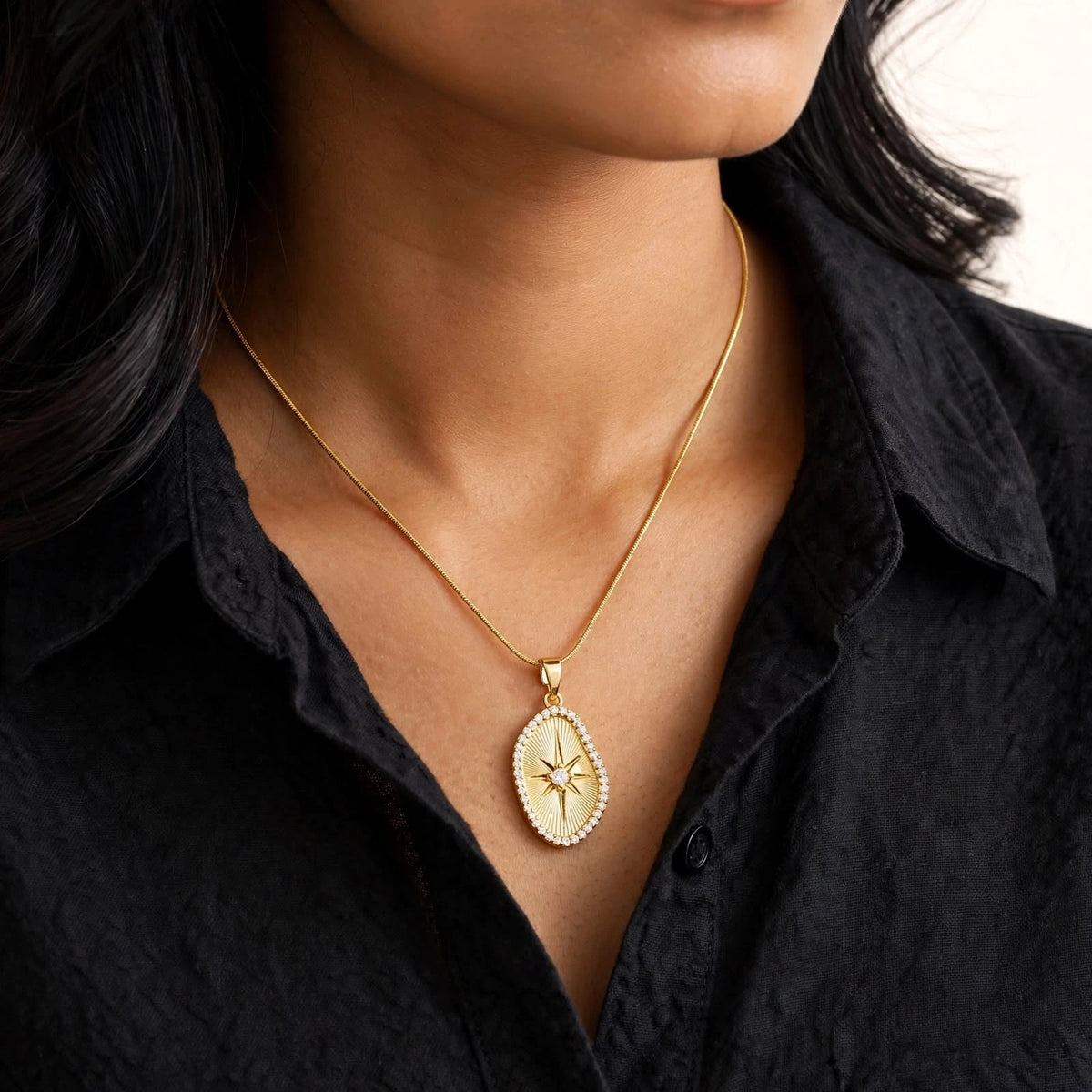 Indian woman in black shirt wearing small sunburst pendant