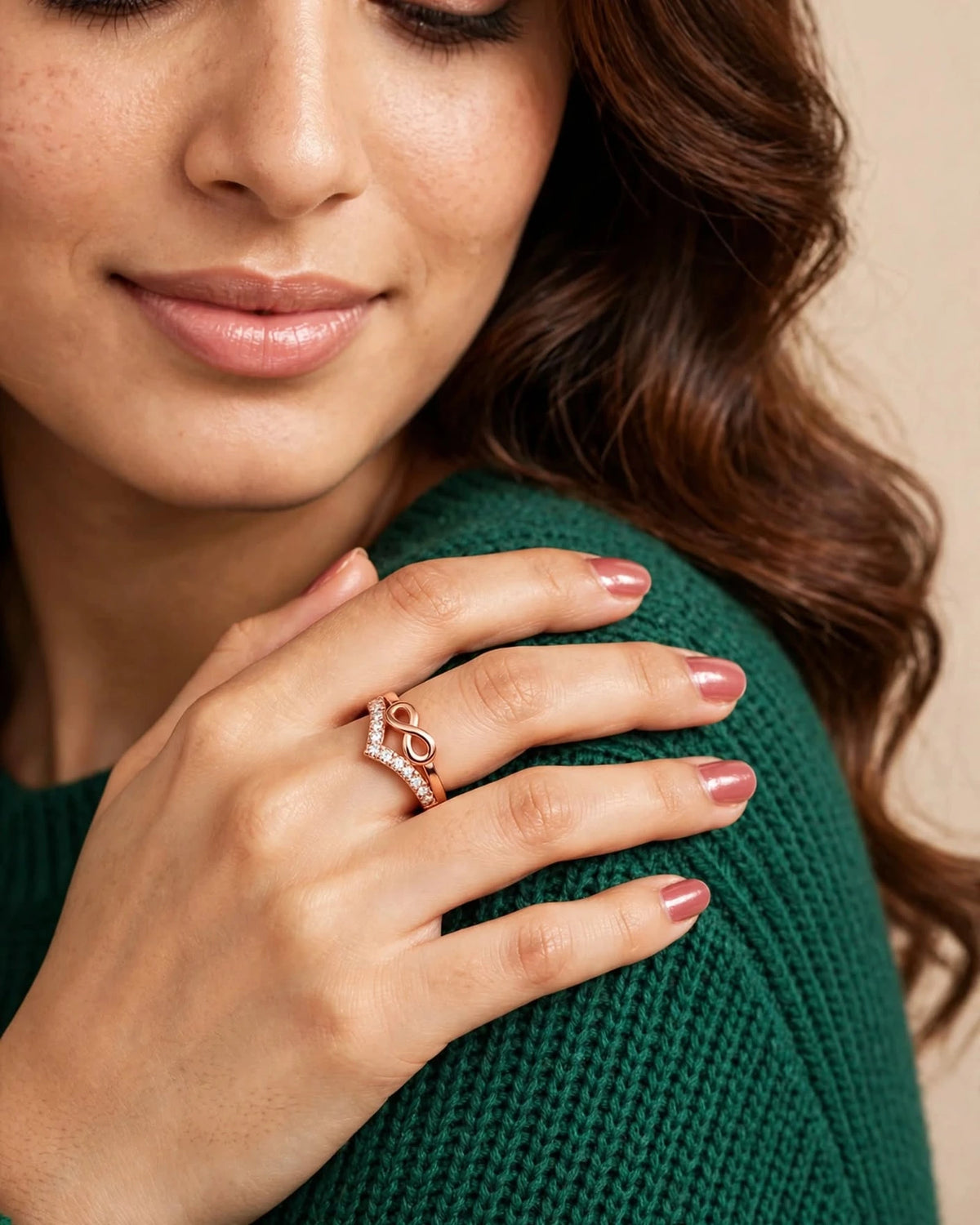 Close crop woman in emerald sweater wearing rose gold infinity CZ ring on shoulder