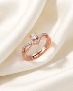 Rose gold V solitaire ring resting on soft ivory silk fold, true small size on warm white