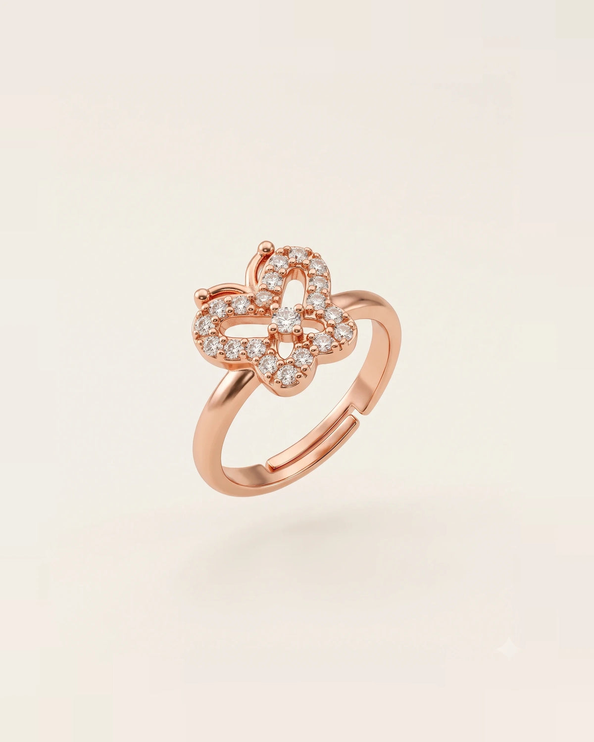 Rose gold butterfly ring with CZ stones floating on an off-white background.