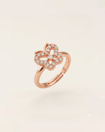 Rose gold butterfly ring with CZ stones floating on an off-white background.