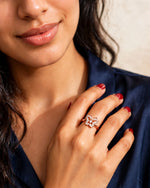 Woman in navy satin blouse with butterfly CZ ring touching collarbone, red nails