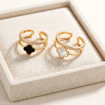 Black and white clover gold rings displayed on ivory linen jewellery tray