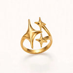 Gold open ring with three starbursts, opening at top, floating on warm off-white background