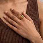 Indian woman in brown ribbed top with small gold triple star ring on finger, hand on chest