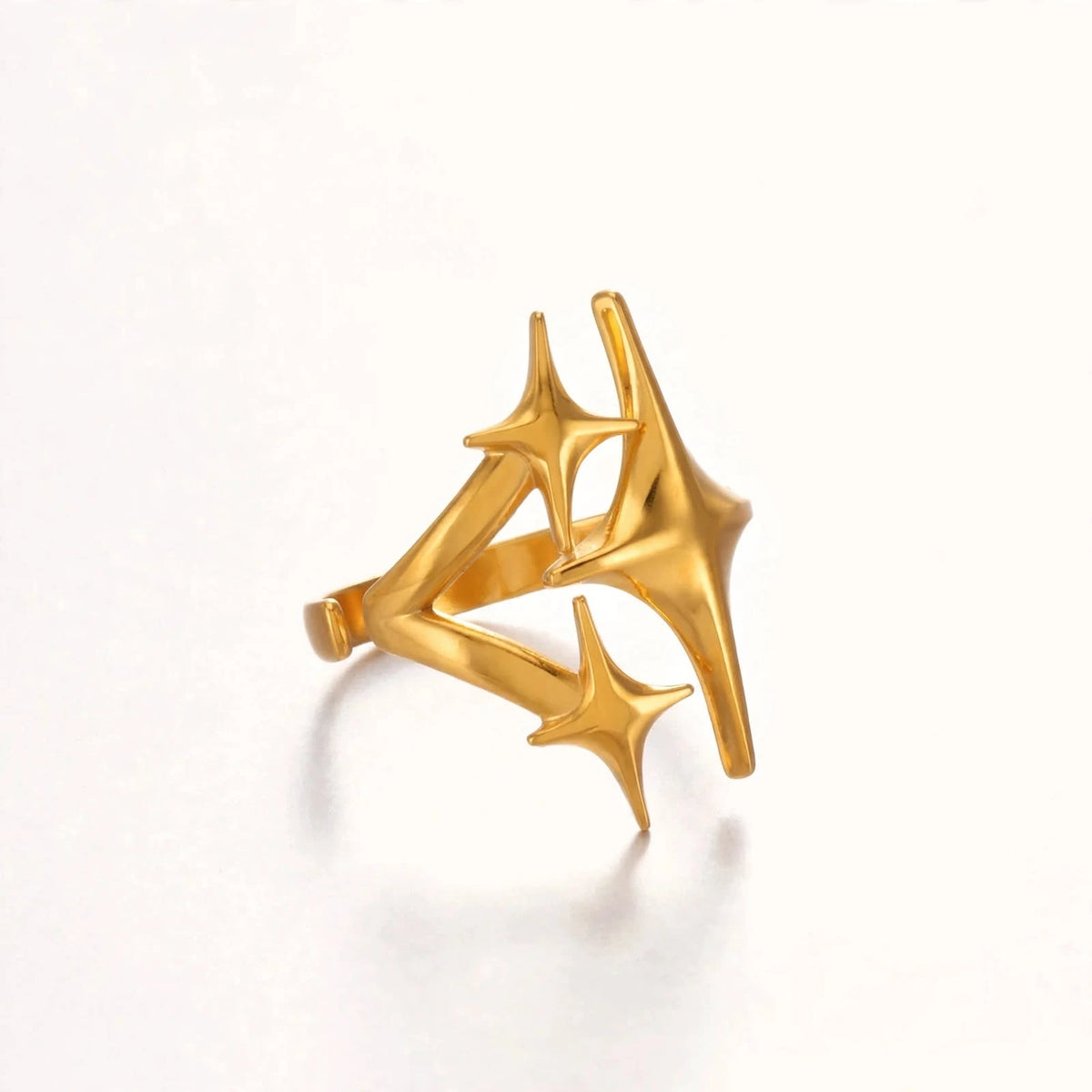 Side profile of gold triple star open ring showing gap and thickness on white background