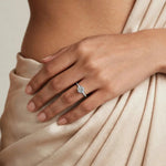 Indian woman's hand with small solitaire diamond ring resting on champagne silk saree at waist