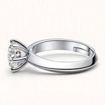 Silver adjustable solitaire ring lying horizontal on off-white surface showing side profile and inner band
