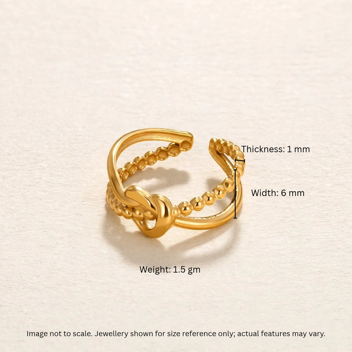 Gold knot ring with width thickness weight callouts on warm off-white background